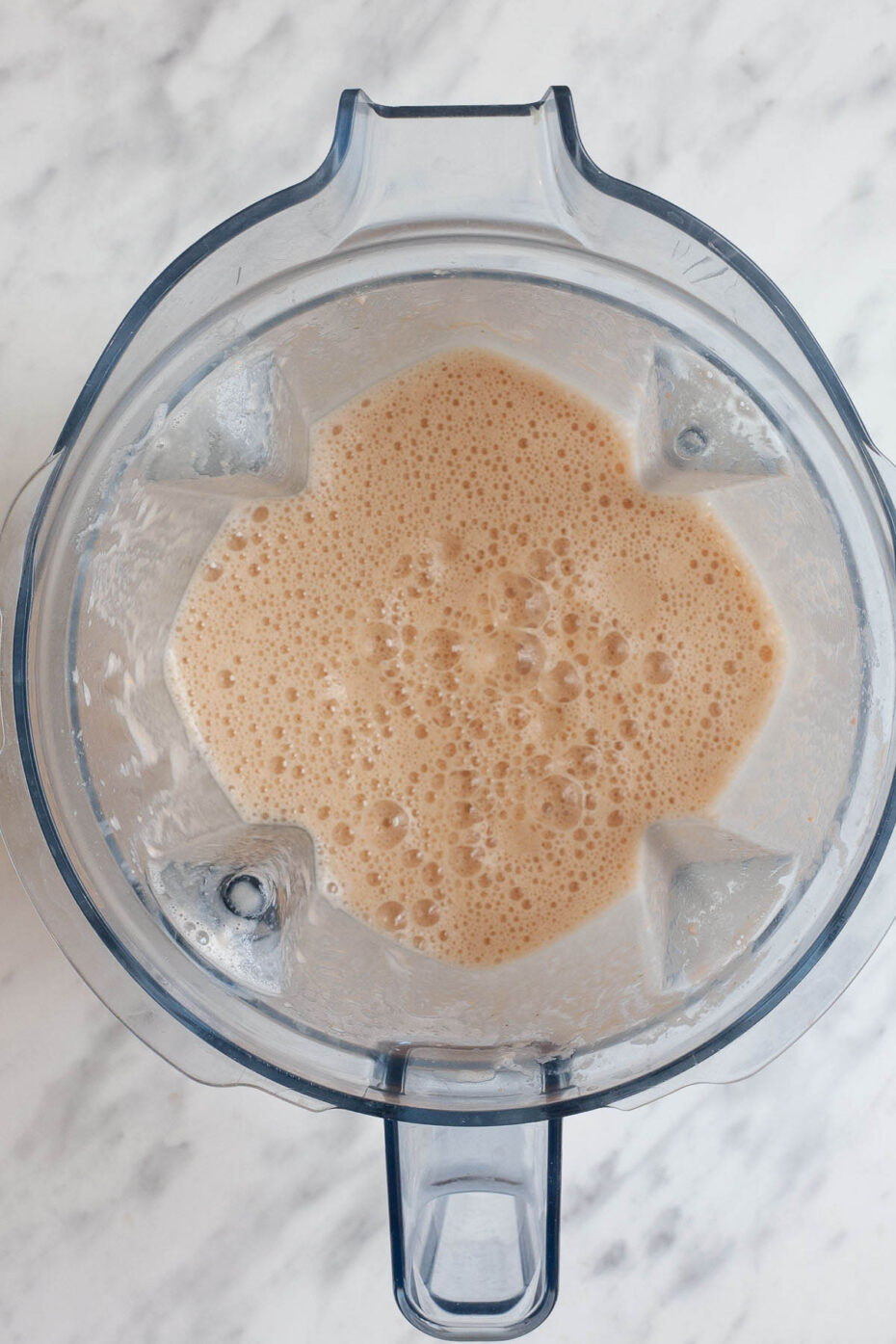 A glass blender from above with a yellowish slightly reddish waffle batter