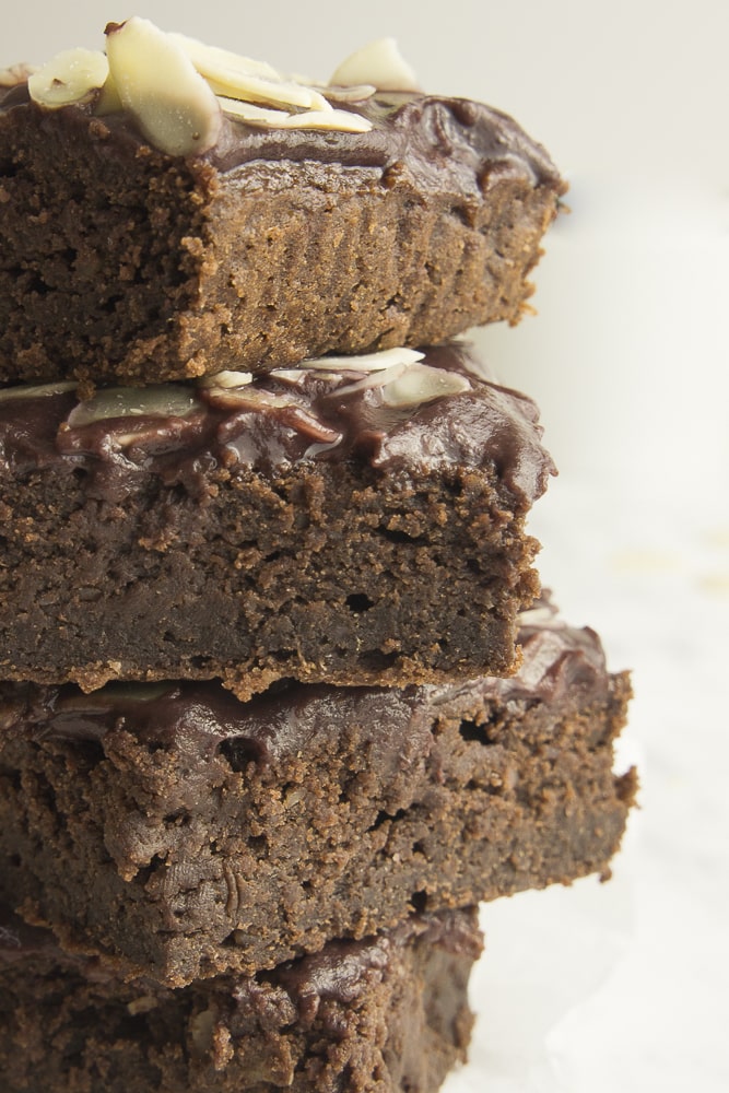 Stack of vegan sweet potato brownies with chocolate frosting and sliced almonds