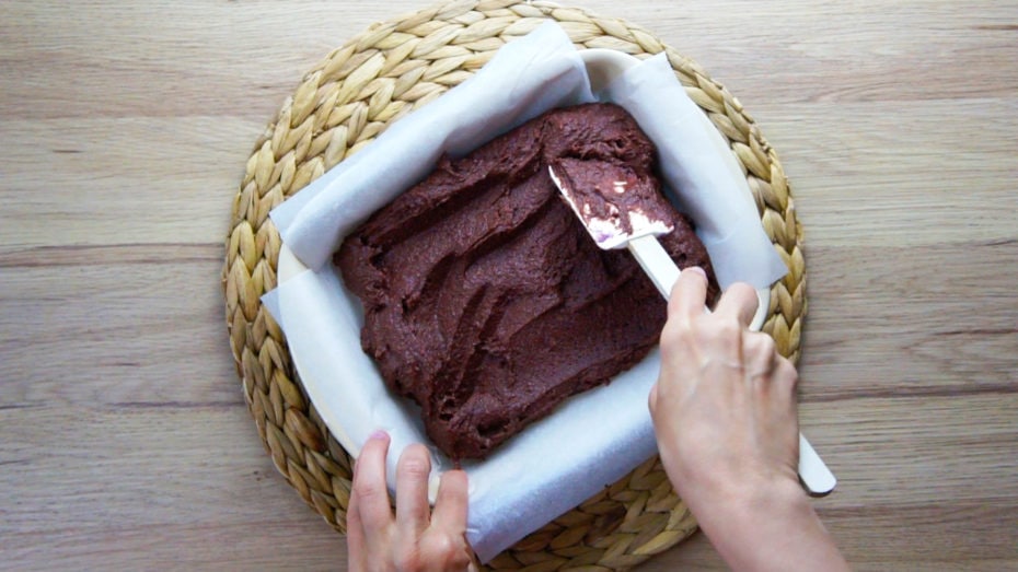 Spreading the brownie mixture with a spatula in an 8x8 pan lined with parchment paper. 