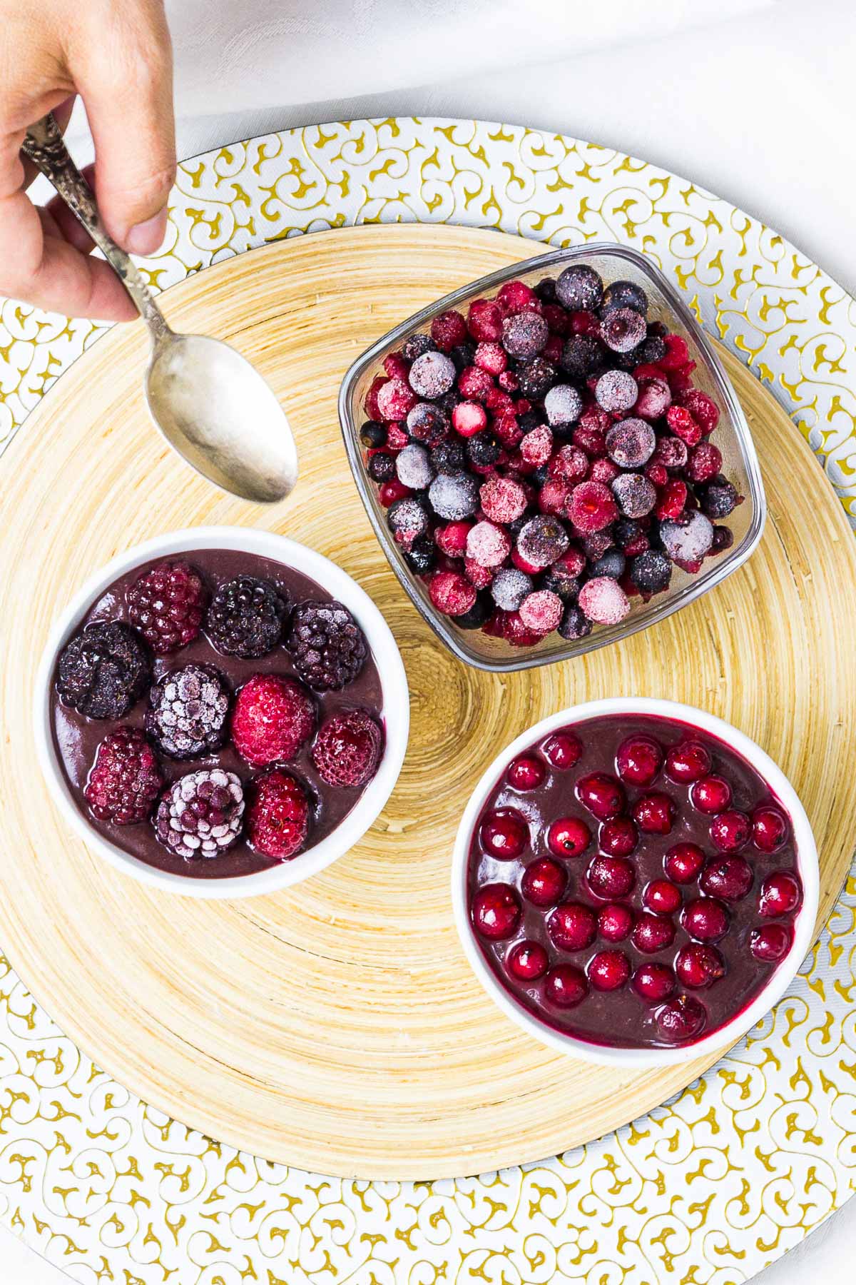 3 small bowls, one with vegan chocolate pudding topped with mixed berries, the other topped with red currant and one bowl is only fruits.