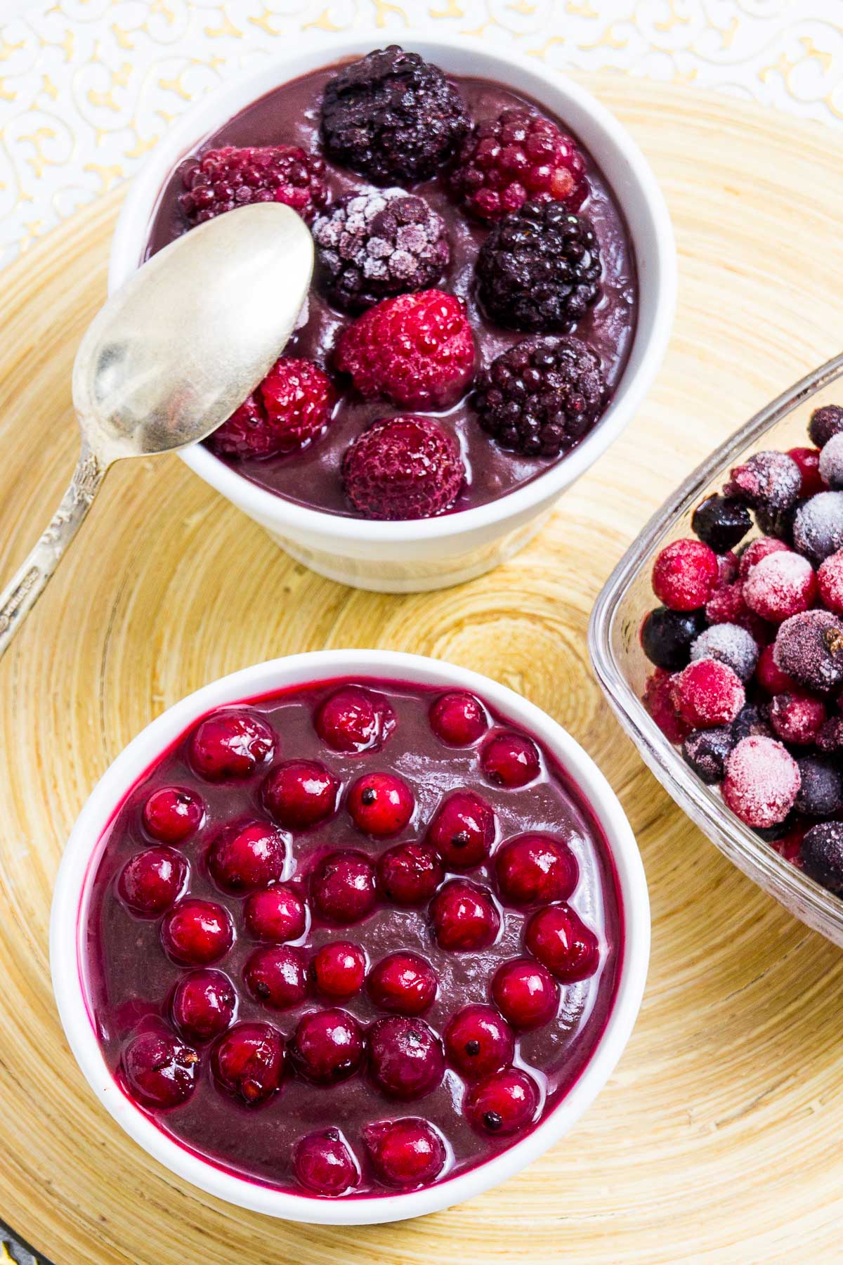 3 small bowls, one with vegan chocolate pudding topped with mixed berries, the other topped with red currant and one bowl is only fruits. 
