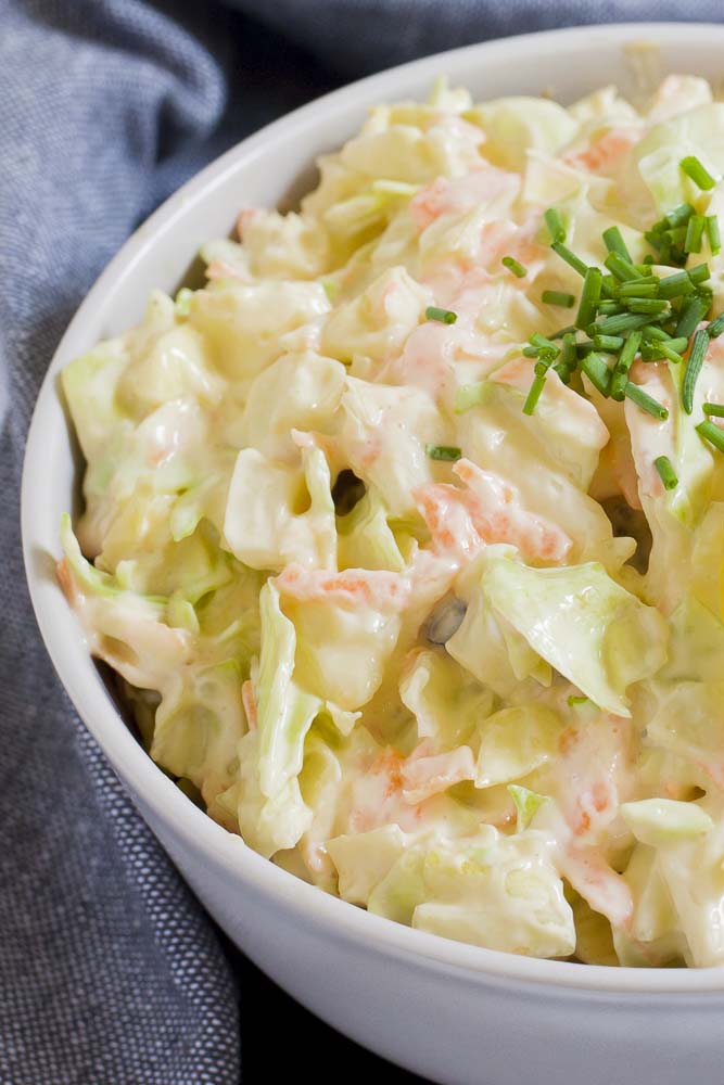 White bowl of shredded cabbage and carrots in a creamy sauce.