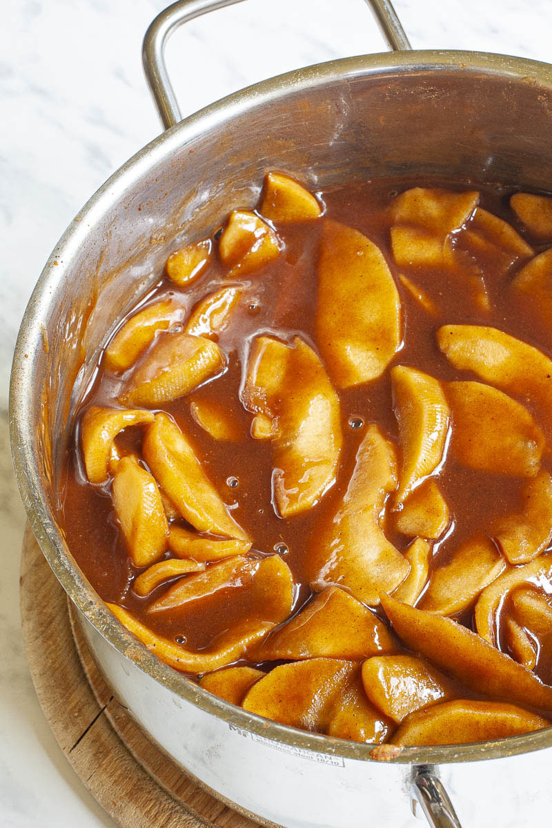 Large saucepan from above containing apple slices cooked in dark brown sauce.