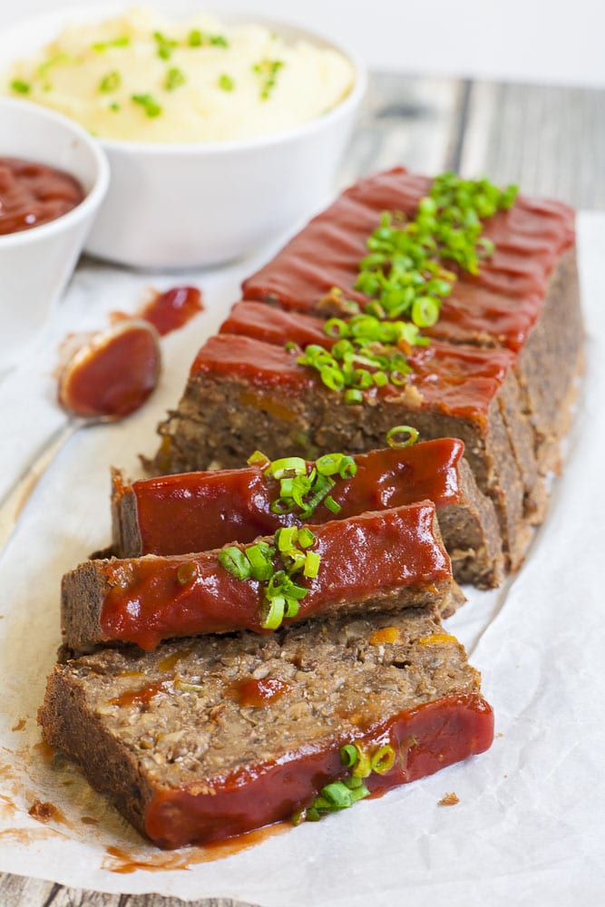 Brown chunky loaf with a red glaze on top and sliced spring onion greens. 3 slices are stacked on top of each other. 