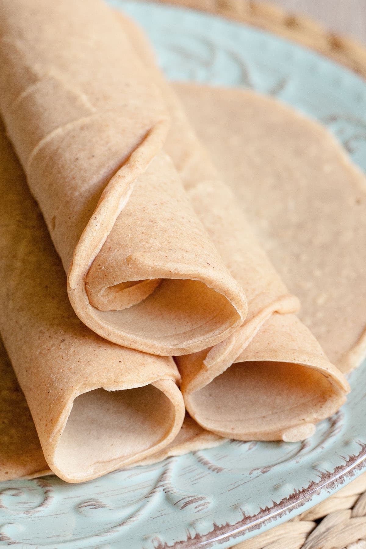 3 rolled tortillas on top of one flat placed on a light blue plate