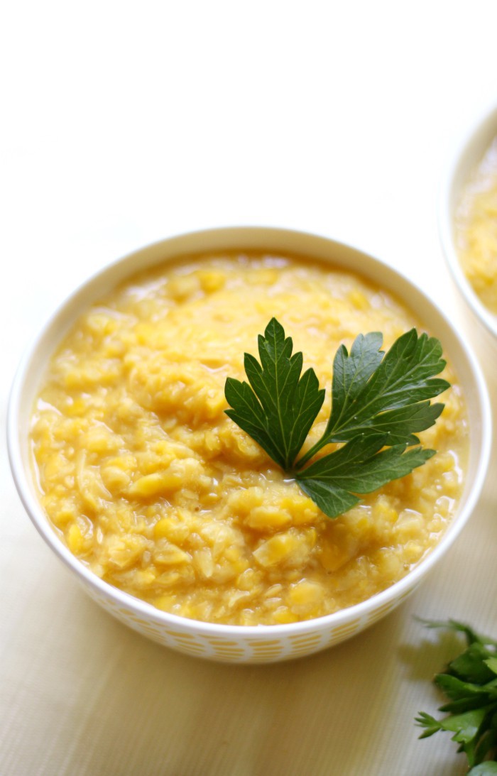 Small white bowl with yellow creamed corn topped with parsley