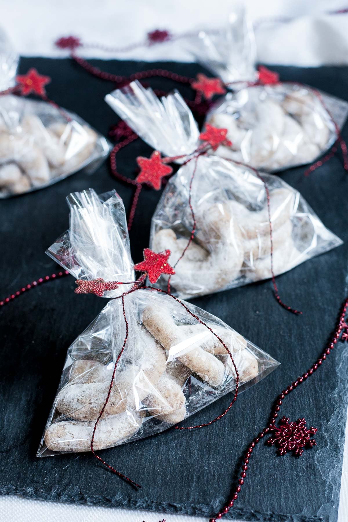 Small plastic packets with crescent-shaped cookies tied with red ribbon and red stars.