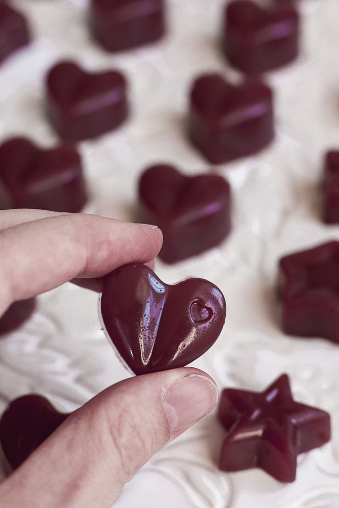 A heart shaped cranberry jelly between two fingers