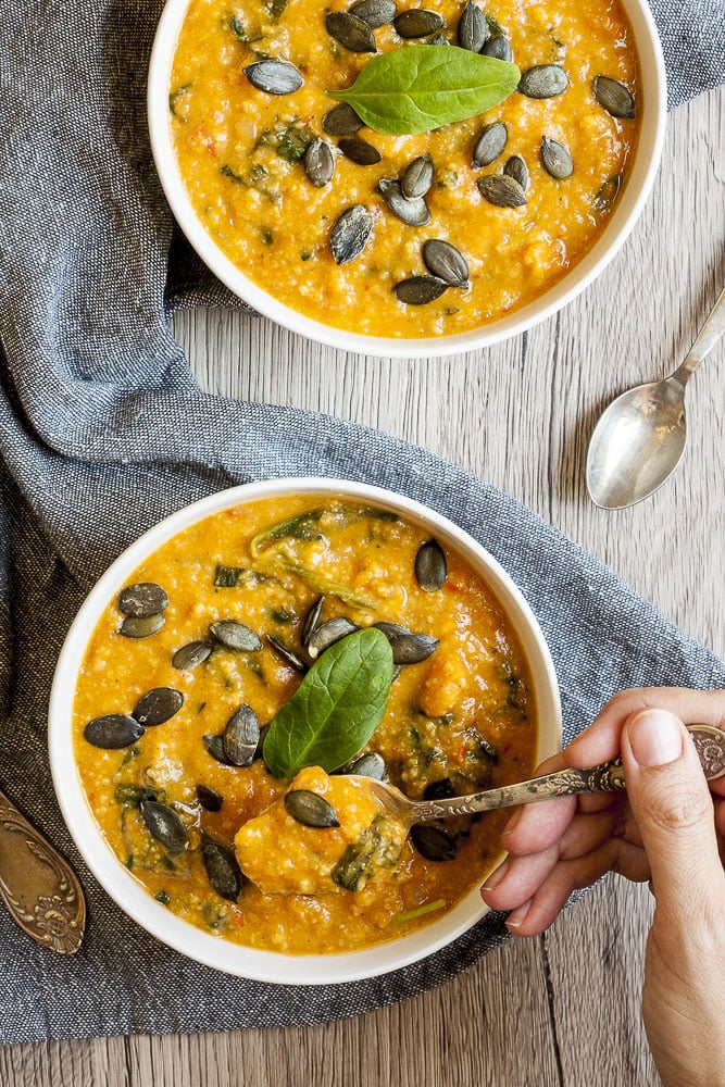 2 white bowl of vegan sweet potato soup topped with pumpkin seeds and fresh spinach