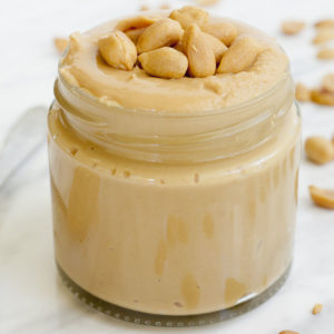 A small jar with light peanut butter topped with chopped peanuts.