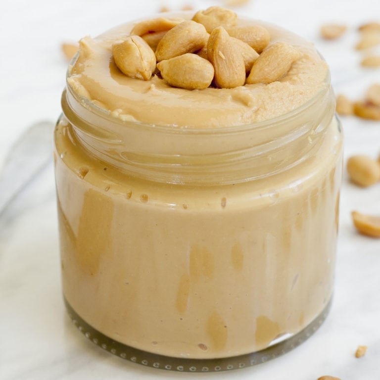 A small jar with light peanut butter topped with chopped peanuts.