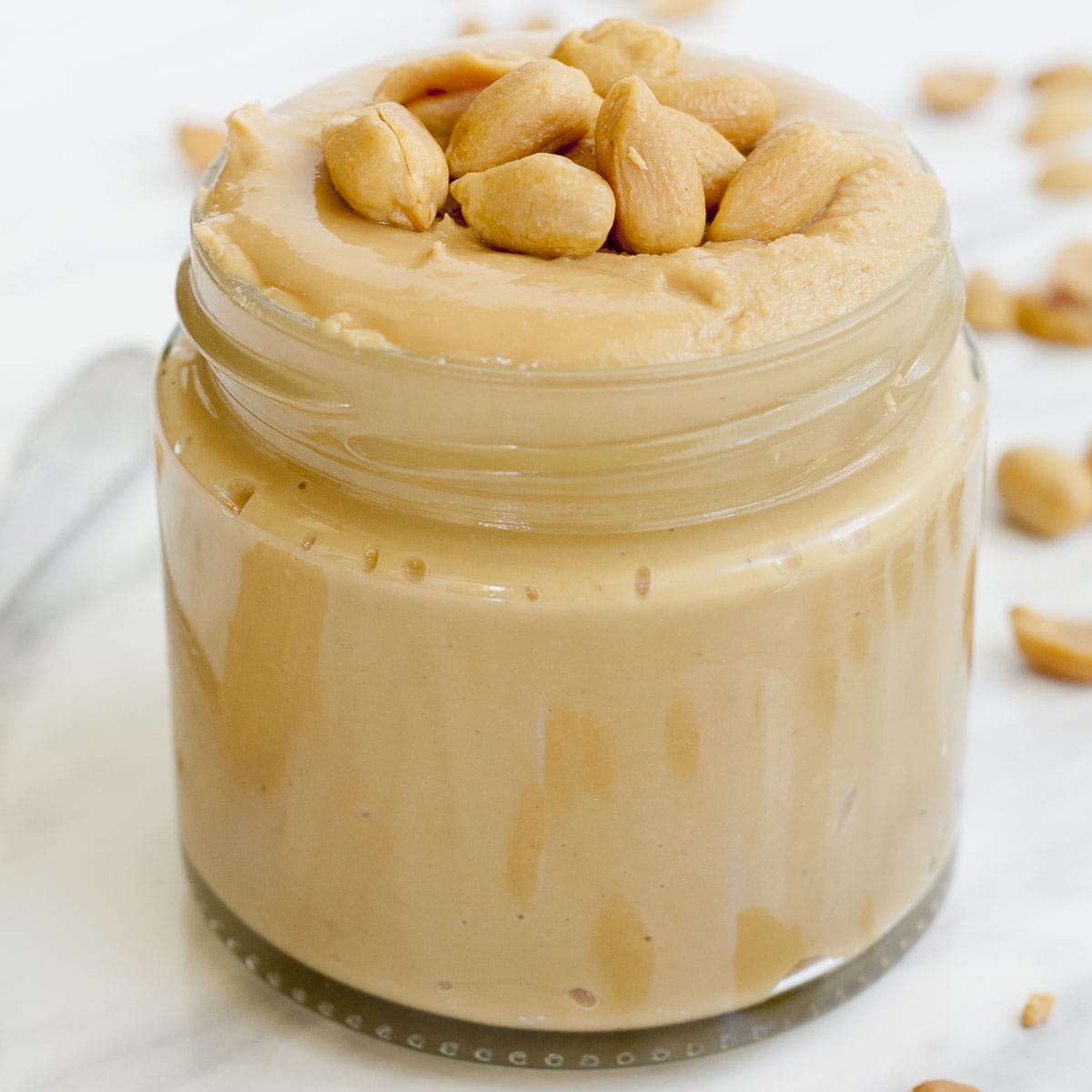 A small jar with light peanut butter topped with chopped peanuts.