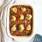 Red sauce topped with stacks of thick white paste sprinkled with freshly chopped green herbs.