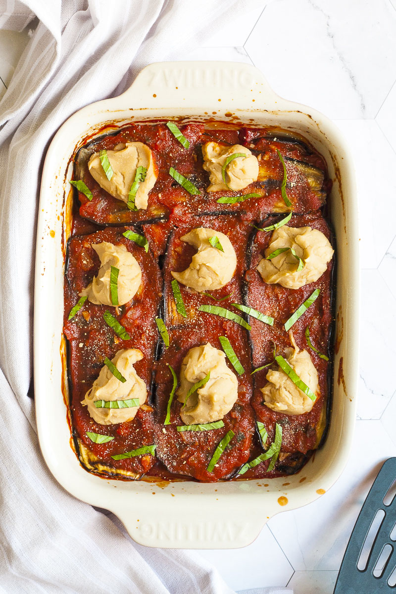 Red sauce topped with stacks of thick white paste sprinkled with freshly chopped green herbs.