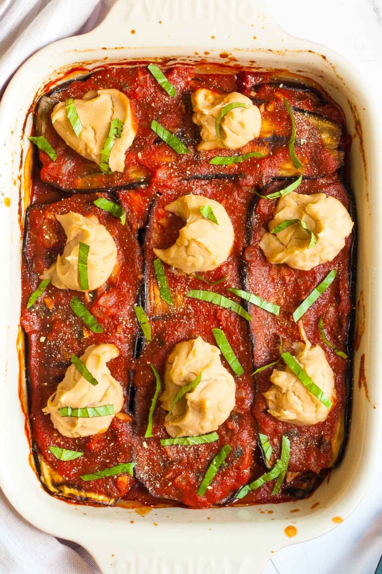 Red sauce topped with stacks of thick white paste sprinkled with freshly chopped green herbs.