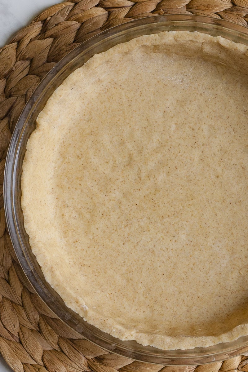 Glass pie pan with brown unbaked pie crust from above