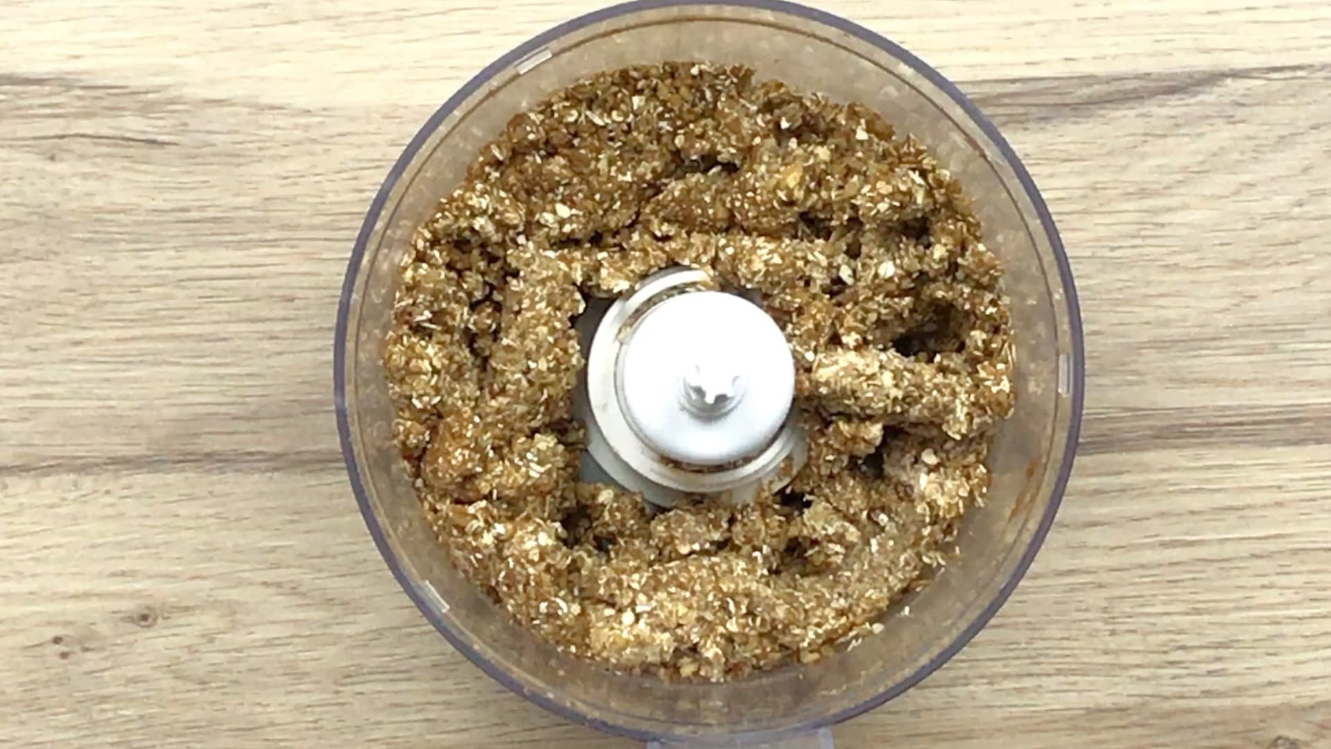 A food processor with a dark brown crisp mixture.