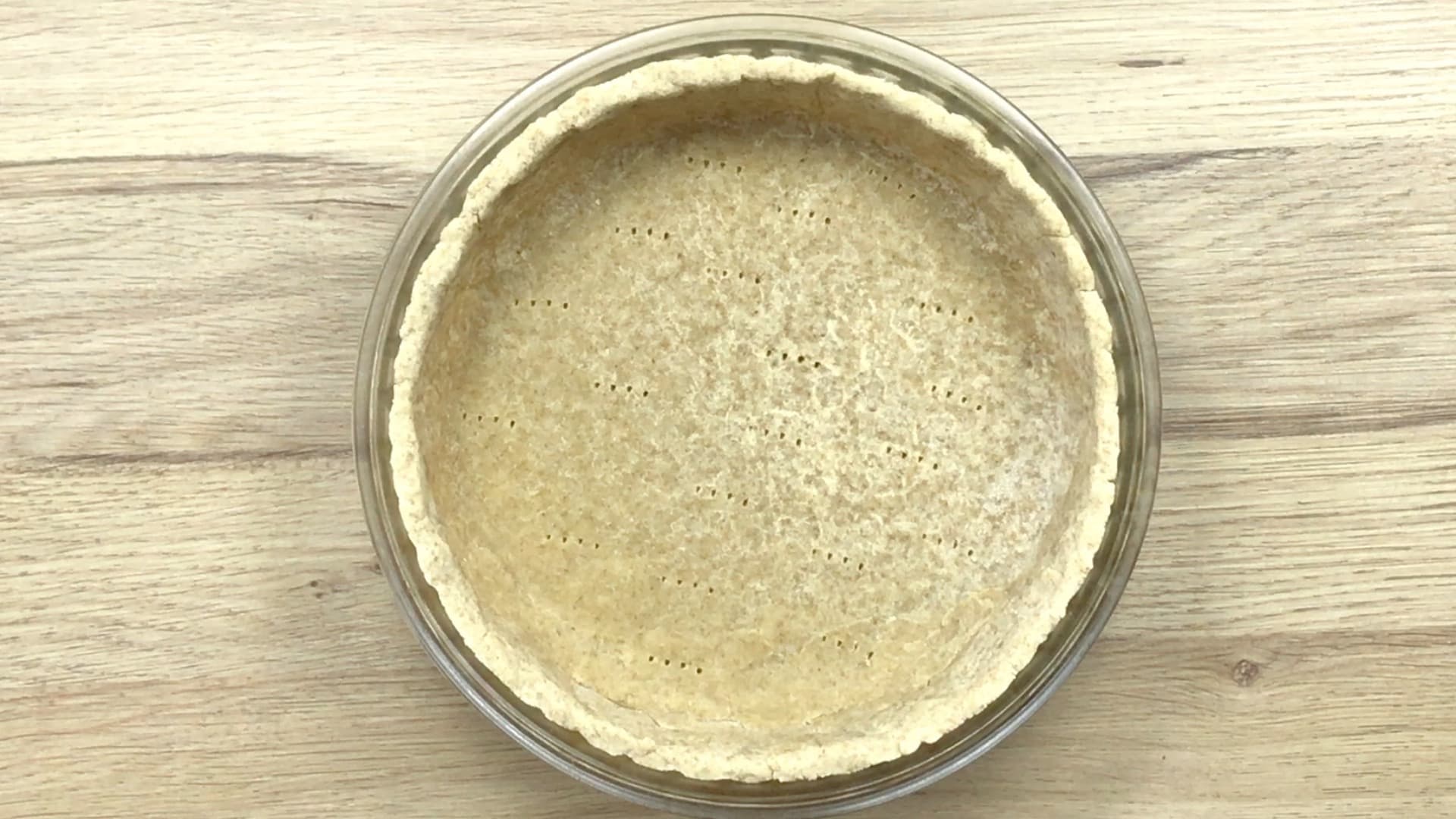 A pie crust in a glass pie pan after prebaked.