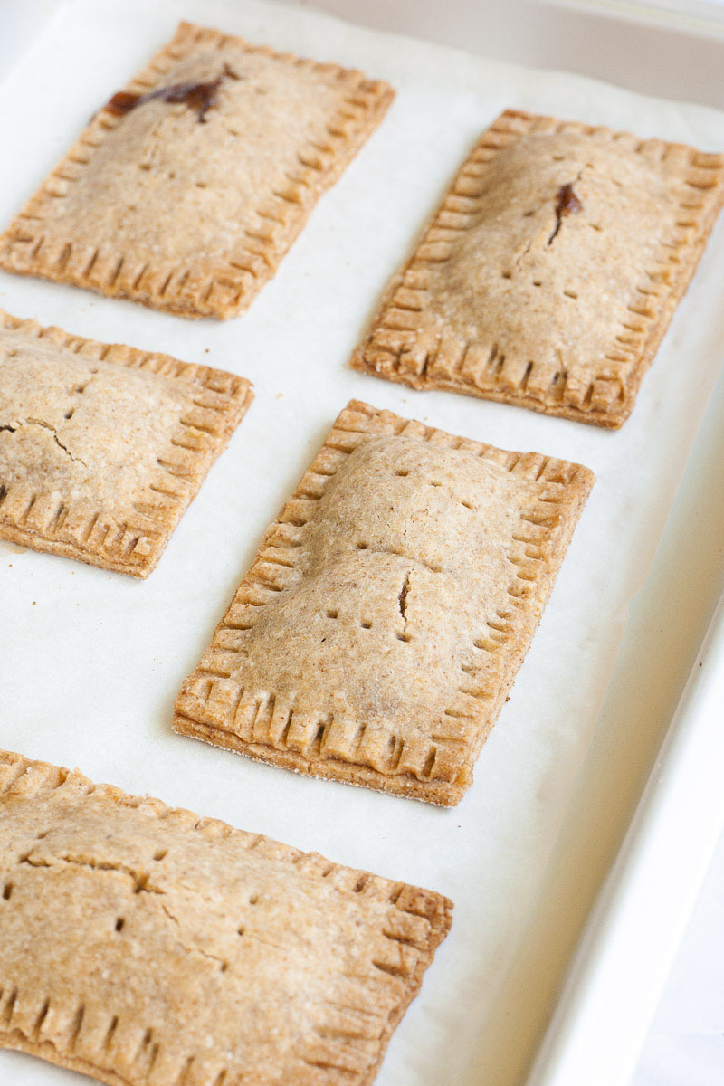 Baked pop tarts, rectangle-shaped pillow-like cookies on a white parchment paper