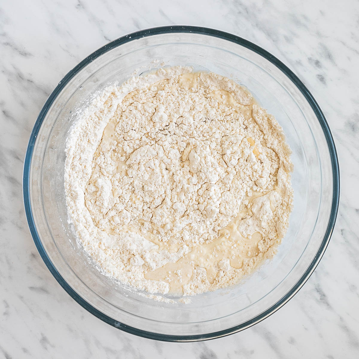 Glass bowl with flour, water, oil, and dry yeast.