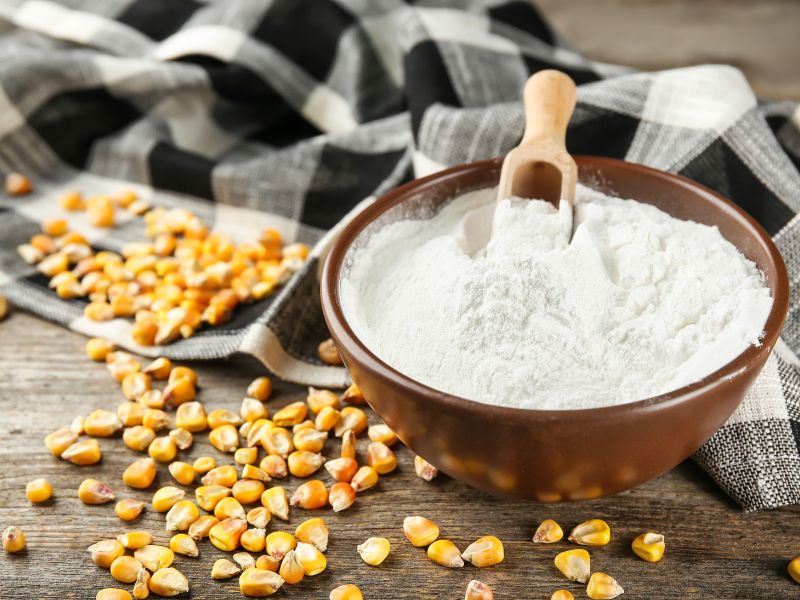 Brown bowl with fine white powder and corn kernels around it