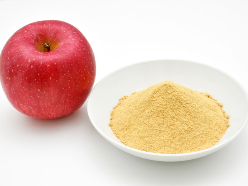 1 red apple and a small white bowl with yellow powder next to it.