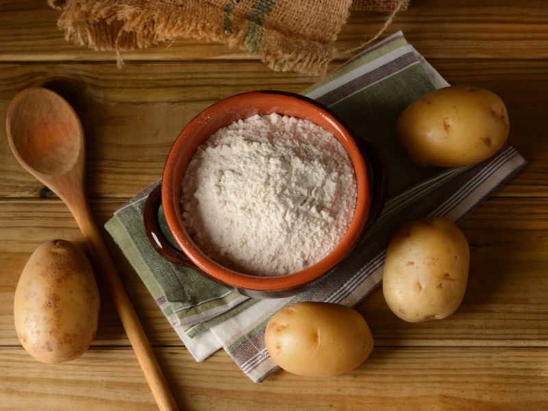 Red bowl with white powder and potatoes around it