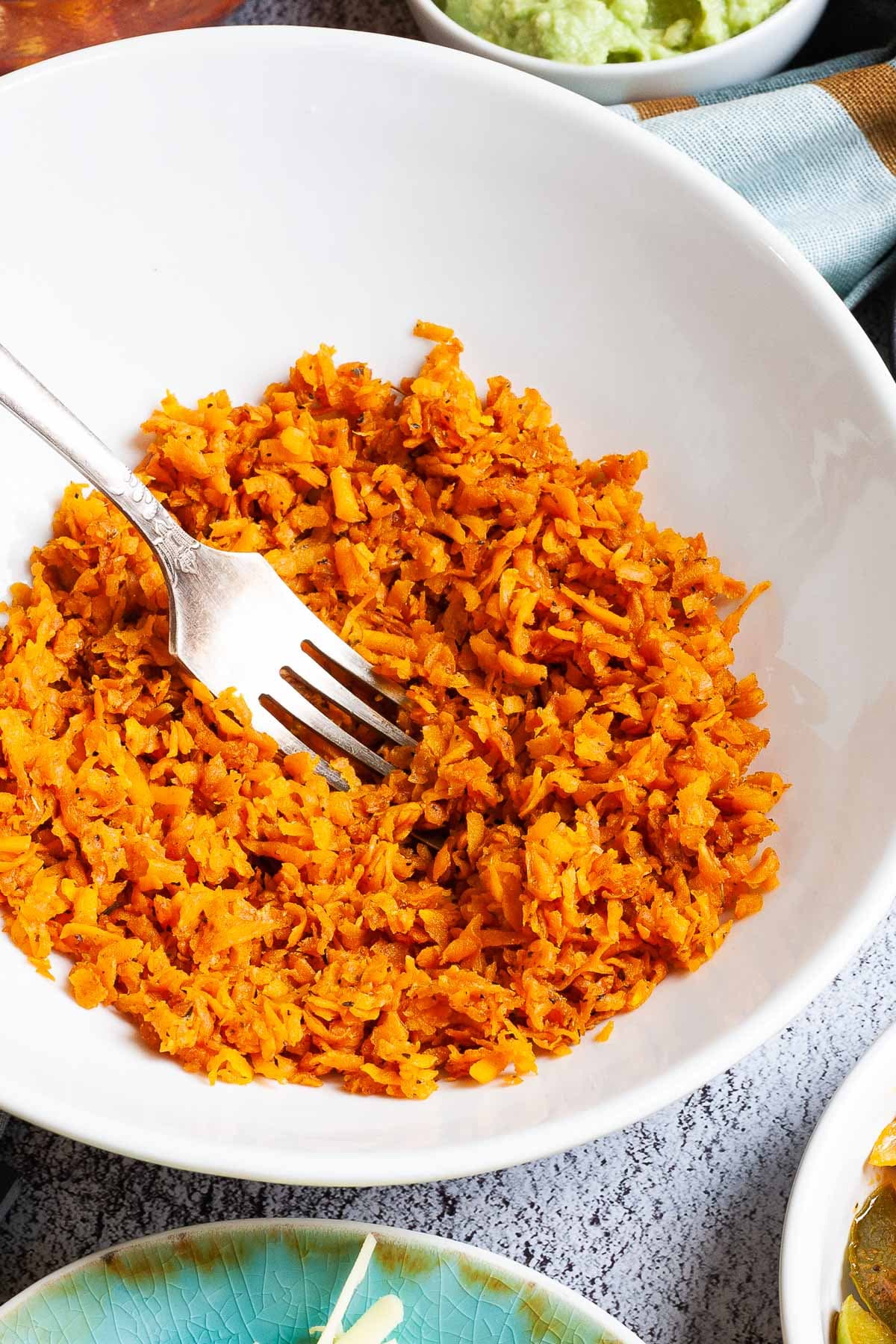 A large white plate with a fork. In the middle, orange riced sweet potato.