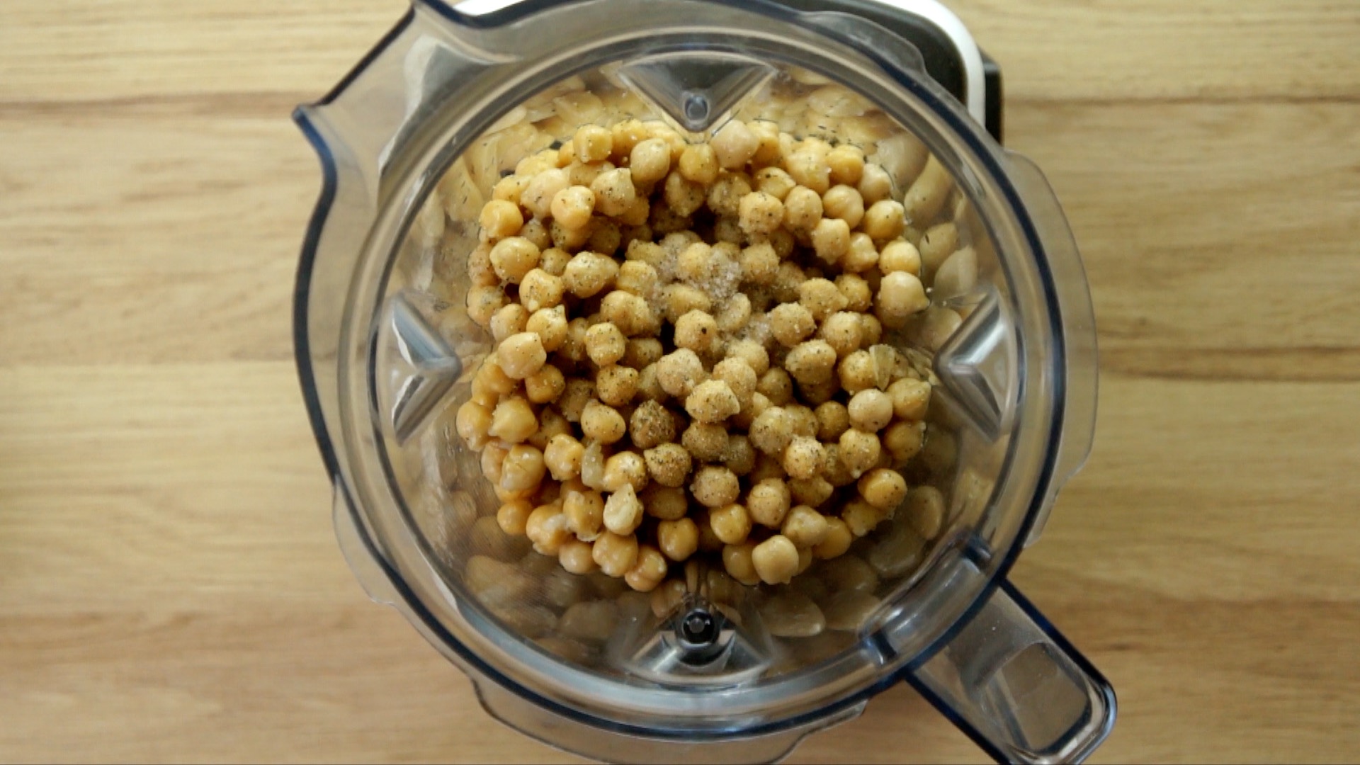 Blender from above with chickpeas, sunflower seeds, garlic clove and liquid.