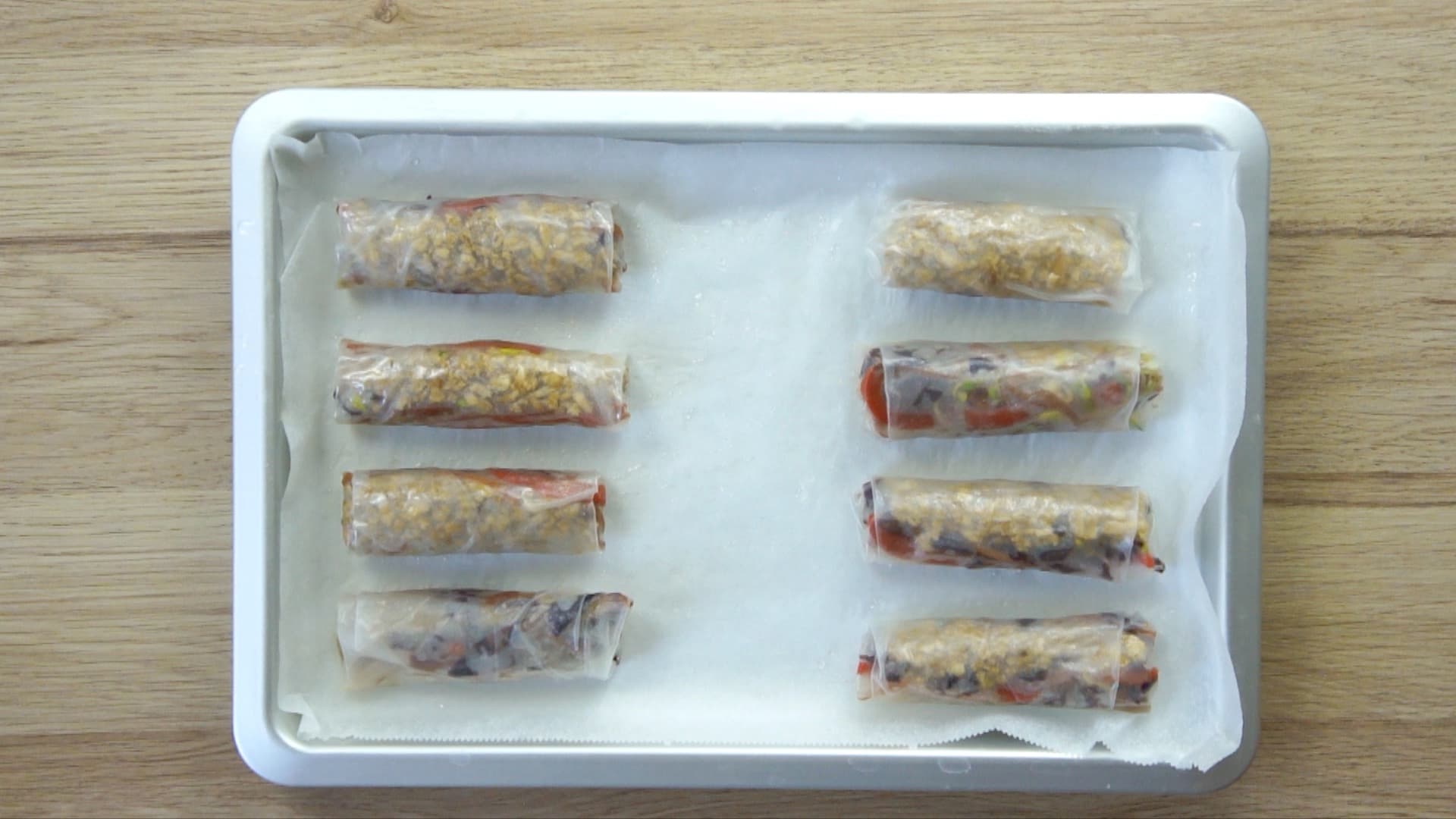 8 rice paper spring rolls on a silver baking tray with parchment paper. 