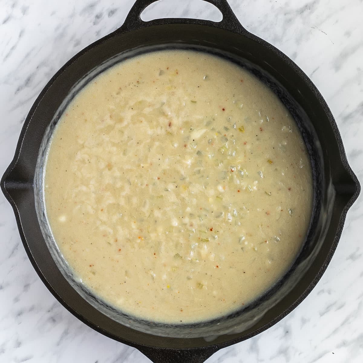 Cast iron skillet with thick light brown chunky sauce.