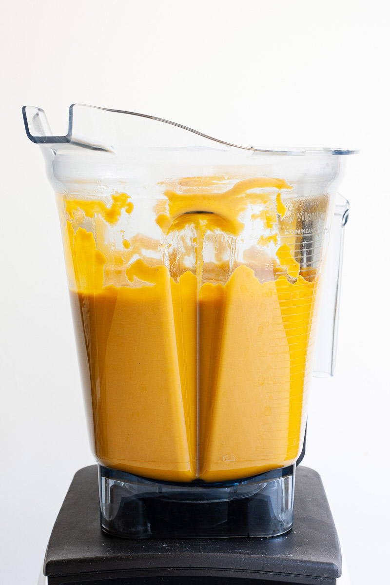 A blender from the side with yellow cream soup