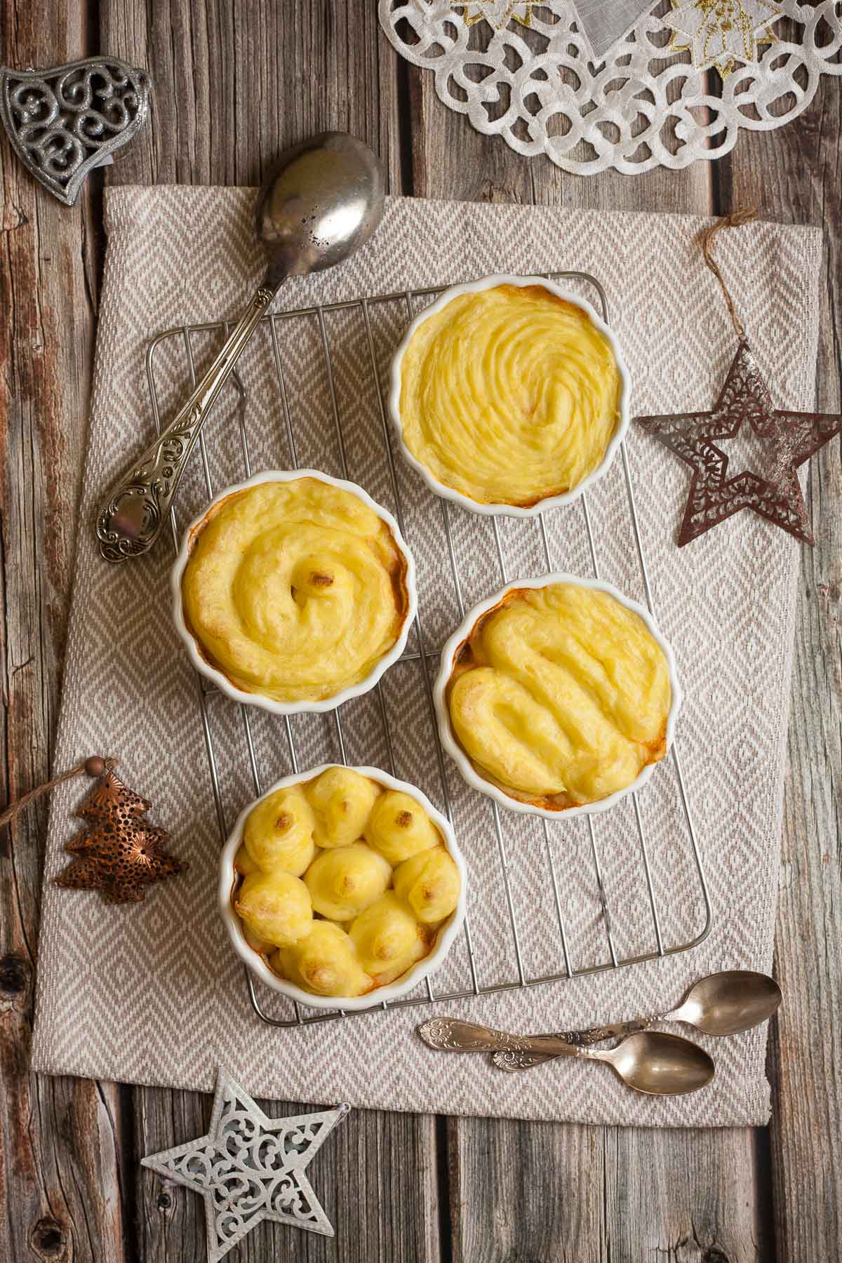 4 white ceramic pots with shepherd's pie from above but only the lovely yellow mashed potato topping is visible.