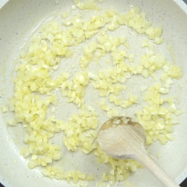 White frying pan with chopped onion.