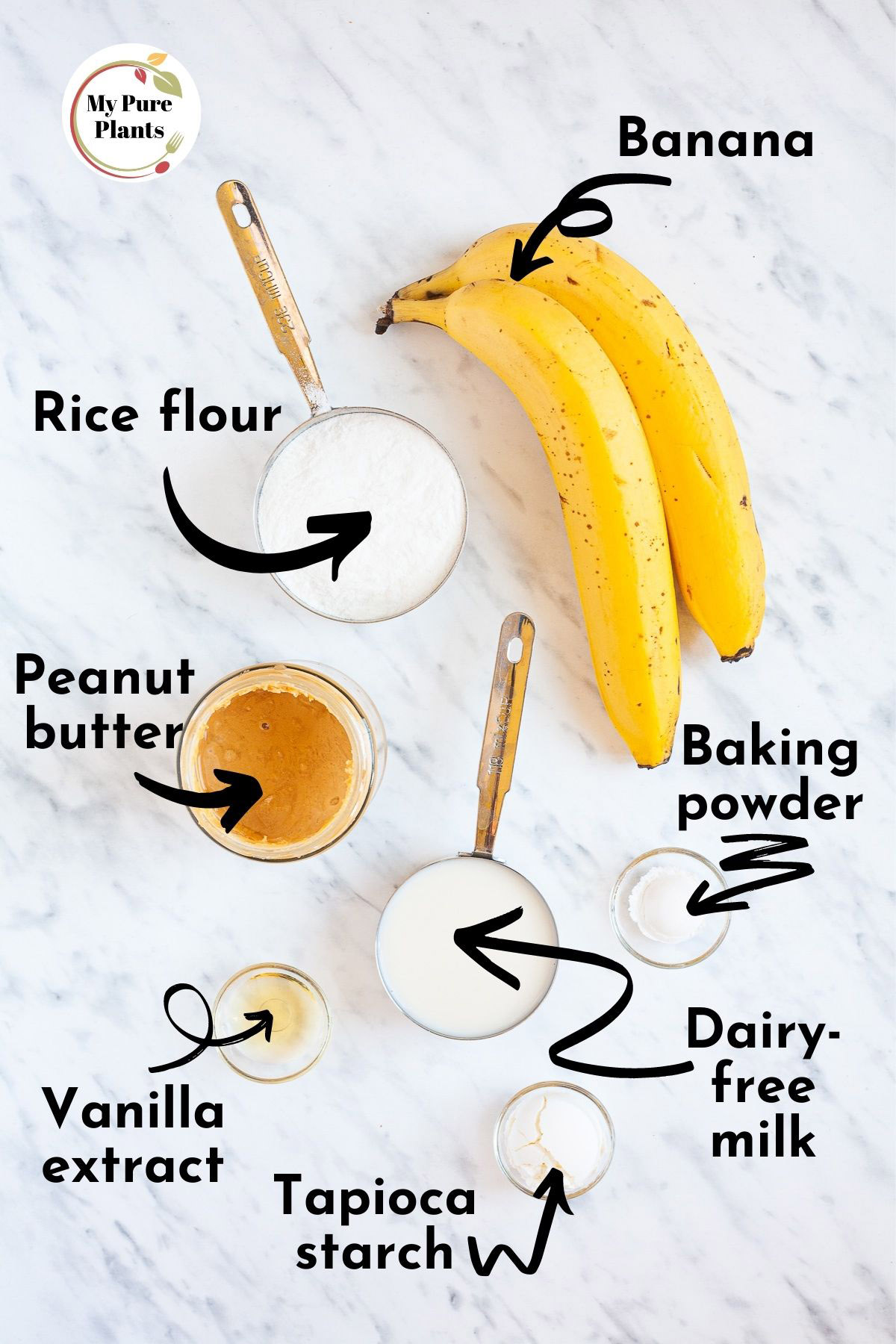Ingredients of vegan banana pancakes from above measured in small containers rice flour, peanut butter, tapioca starch, vanilla extract, baking powder and 2 yellow bananas