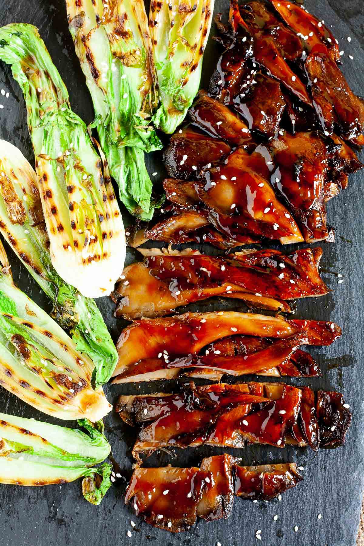 Black boardabove with crispy brown juicy flattened oyster mushroom clusters and half bok choy with charcoal stripes