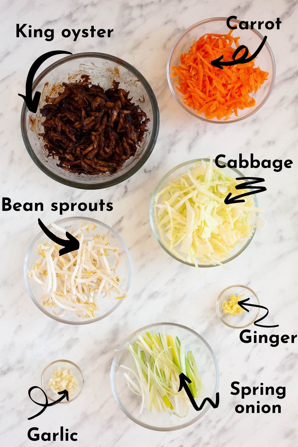 The ingredients of these vegan rice paper dumplings are measured in small glass bowls like shredded carrots, cabbage, julienne spring onion, bean sprouts, and shredded oyster mushroom in dark brown sauce, minced ginger and garlic