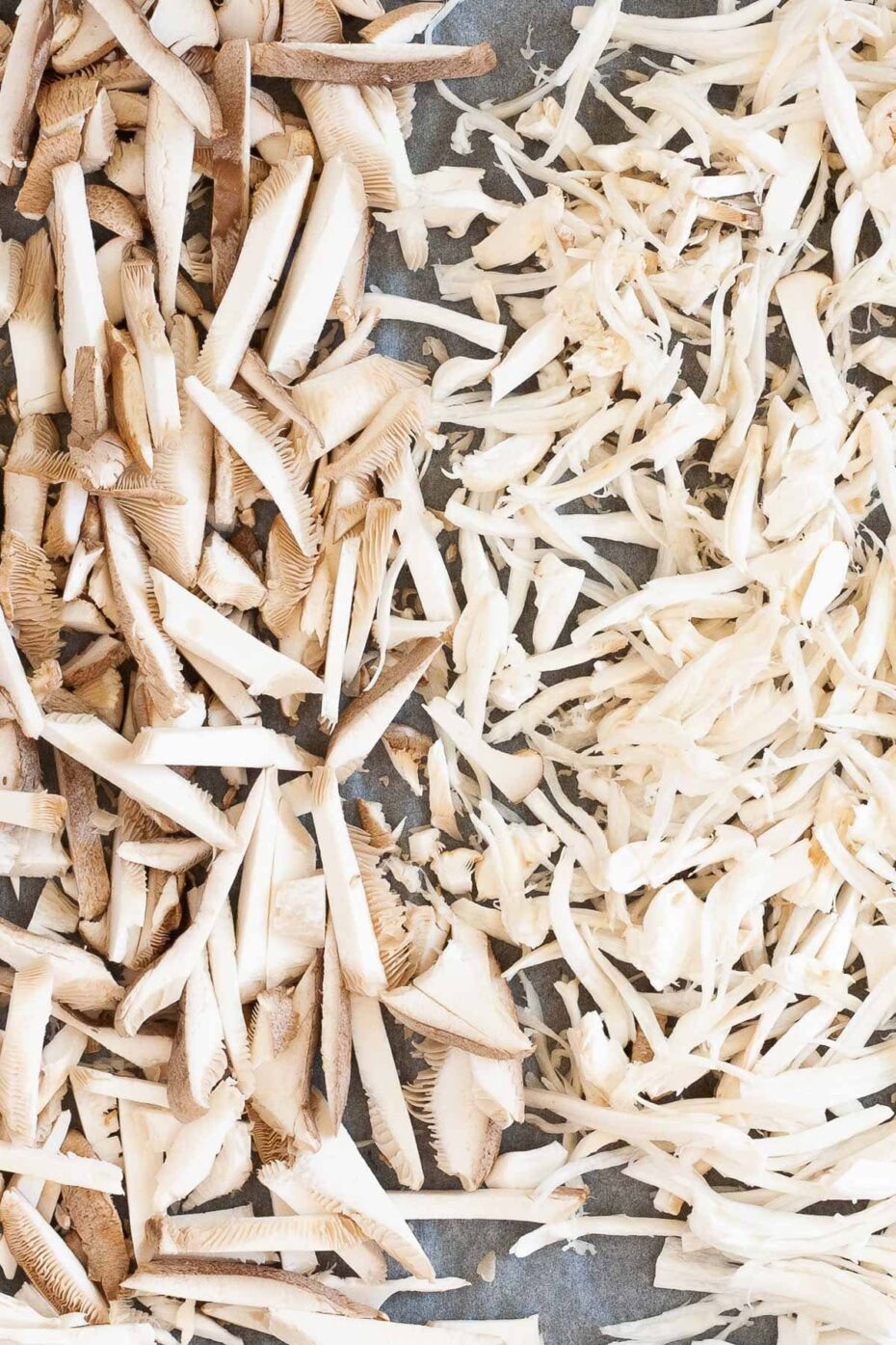 A parchment paper is full of white shredded mushrooms.