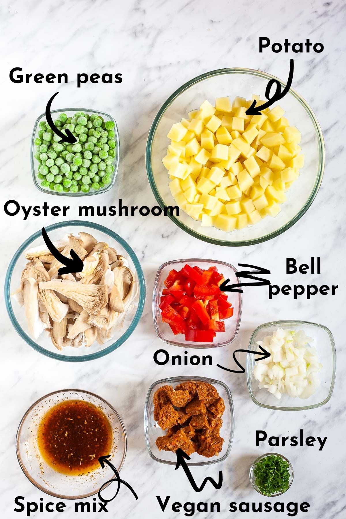 Several glass bowl with the different ingredients to make vegan breakfast hash like chopped yellow potatoes, green peas, mushroom strips, chopped red bell pepper, sliced sausages, chopped white onion, marinade, and parsley