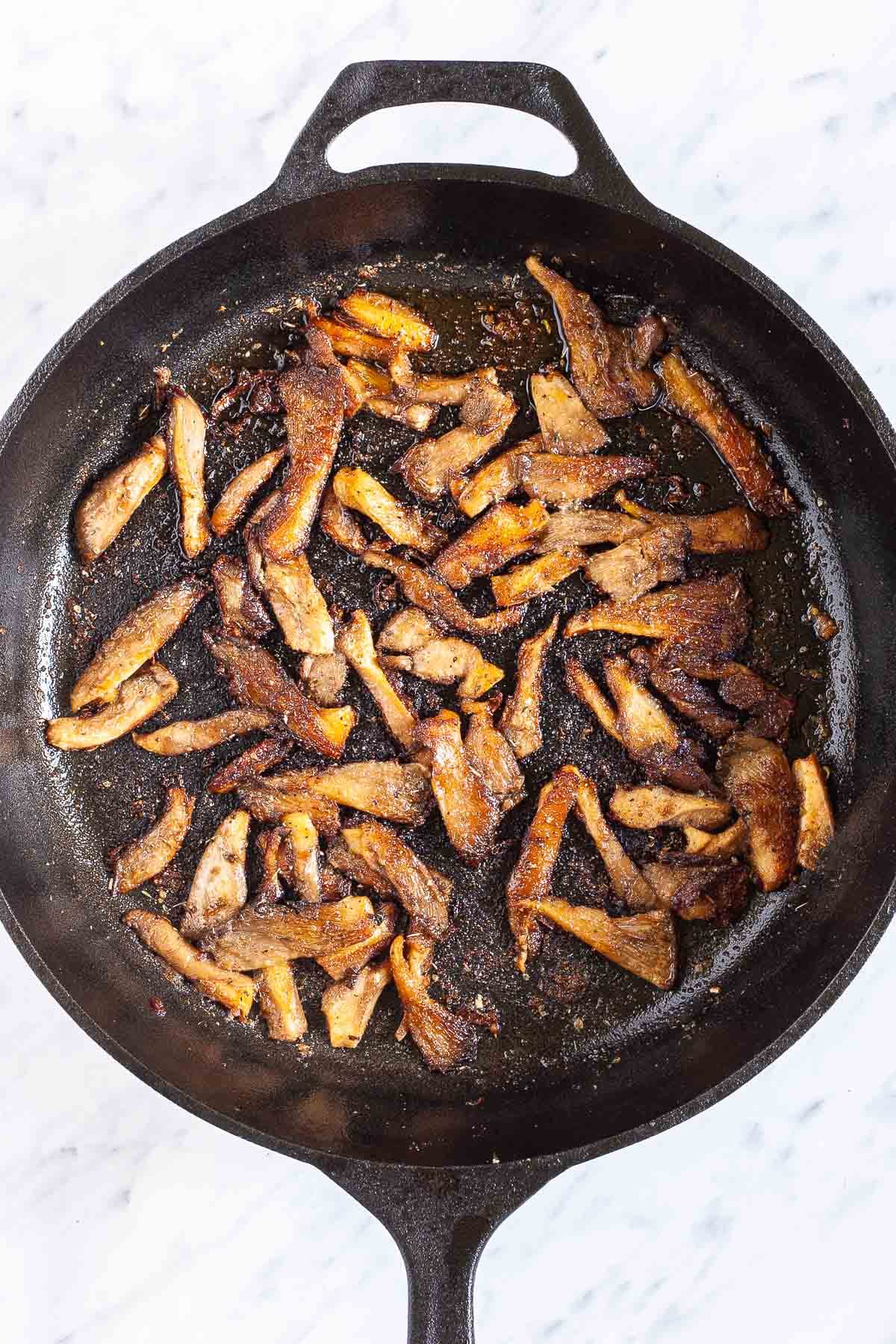 Black cast iron skillet from above with crispy brown oyster mushroom