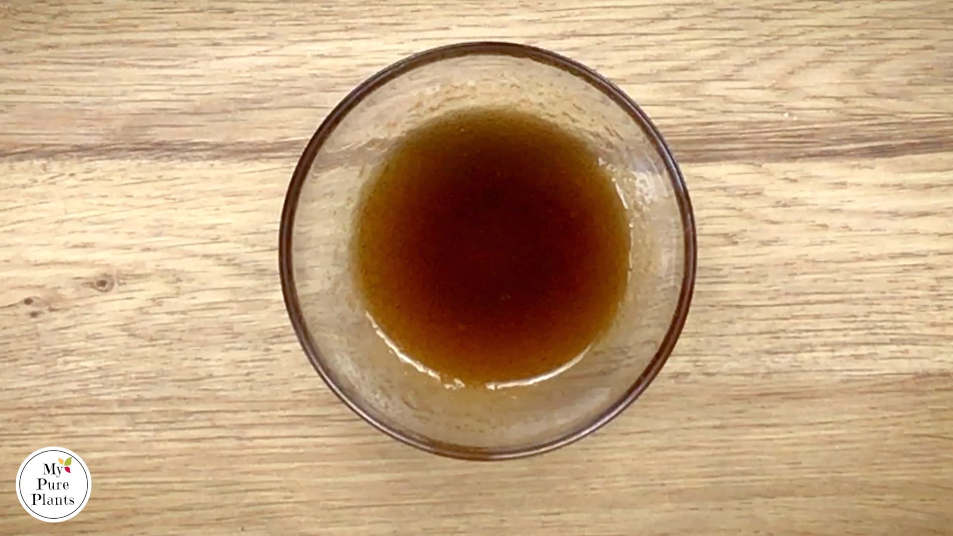 A small glass bowl with dark thin sauce. 