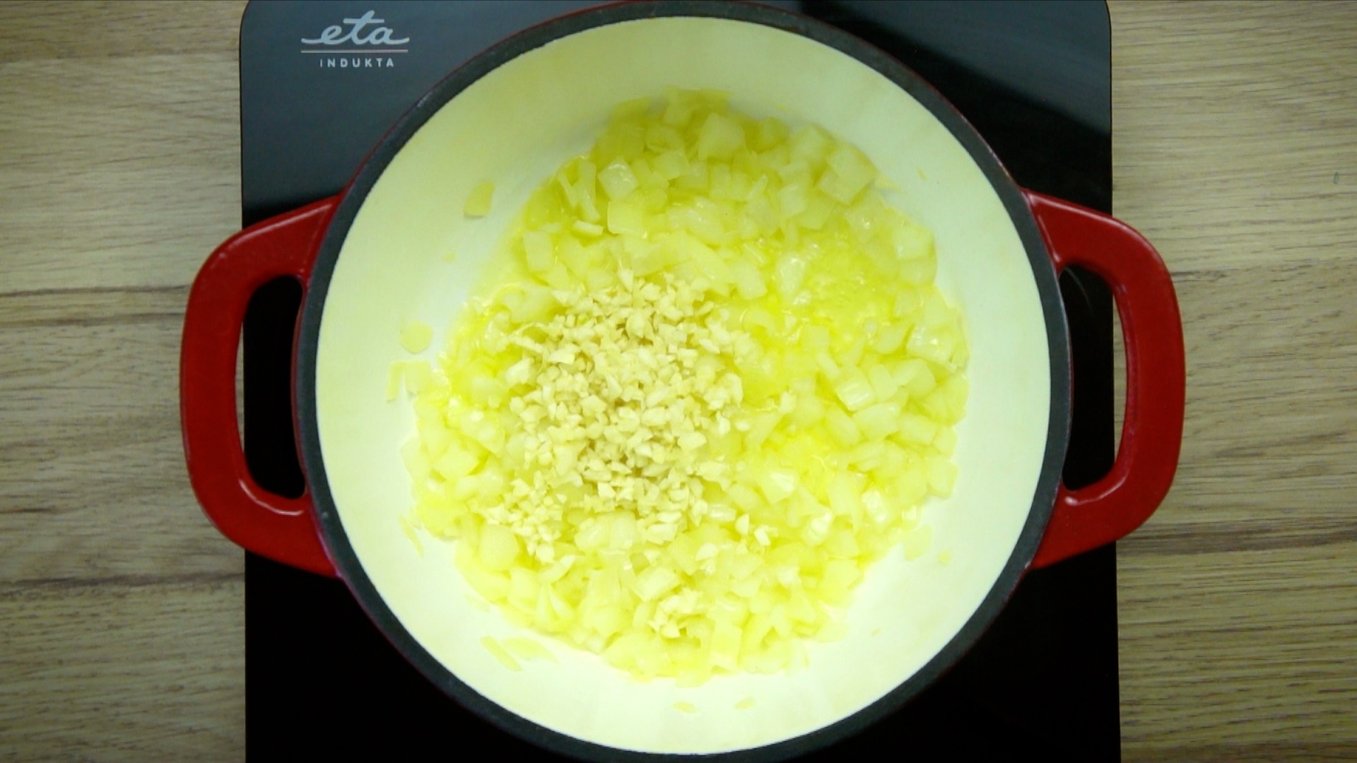 White stockpot with chopped onions and garlic.