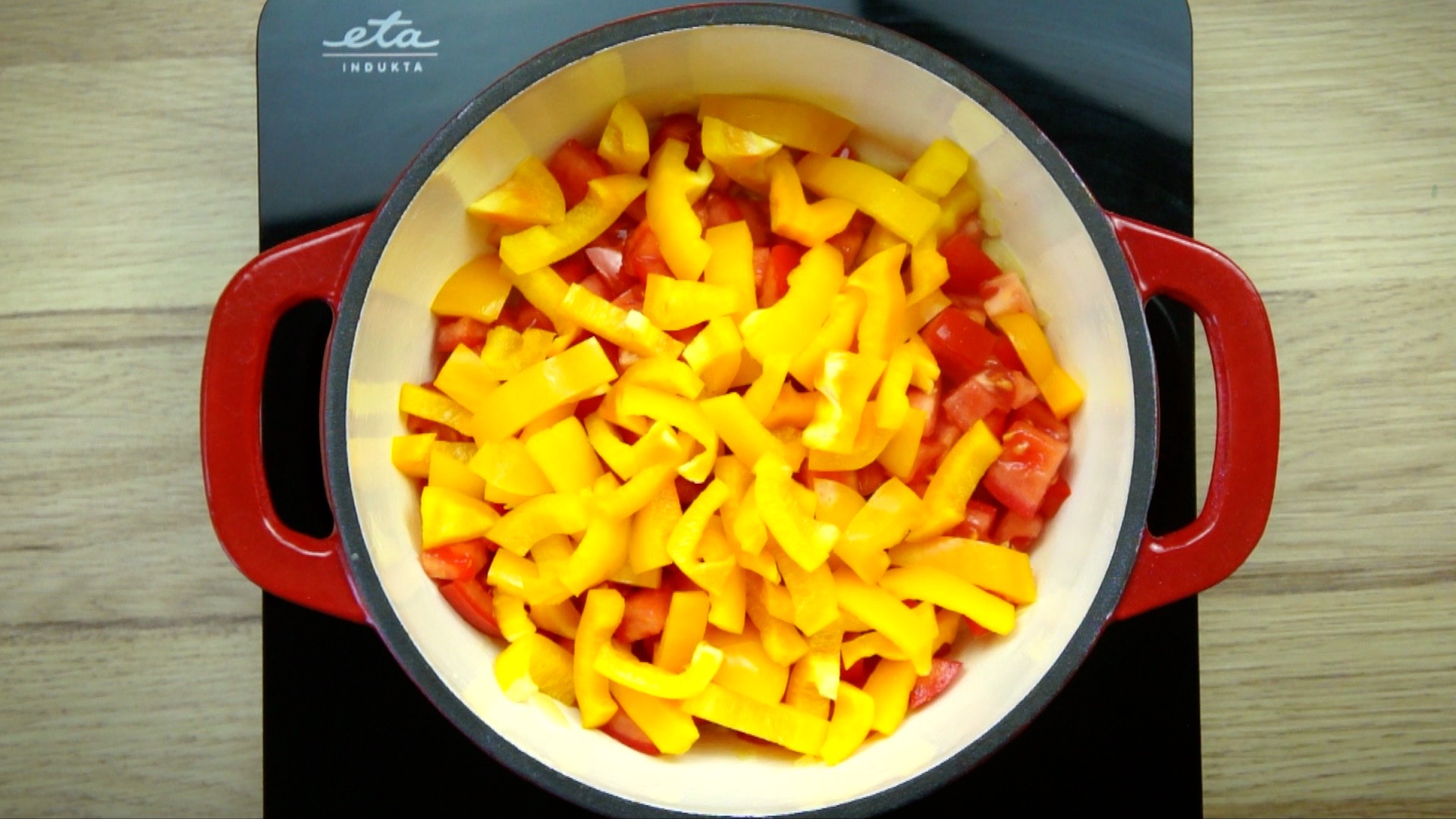 White stockpot yellow bell peppers and red tomato slices.