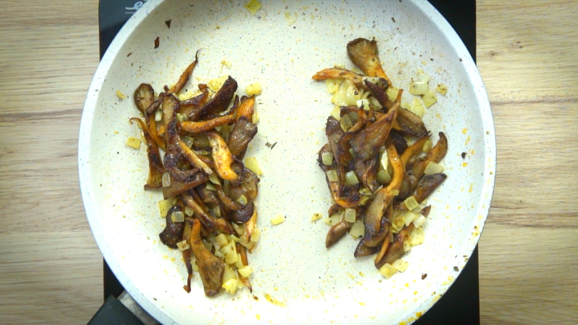 Shredded mushrooms separated into two parts in a white frying pan.