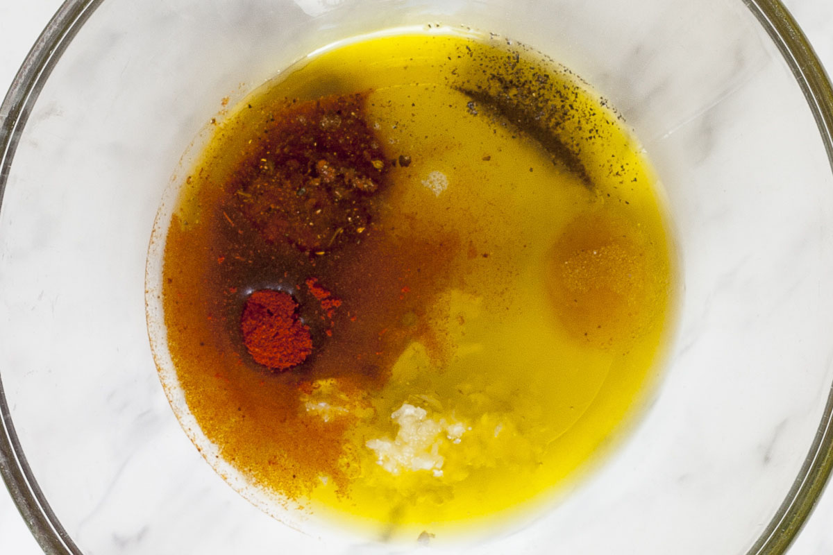 Glass bowl with oil and different colored spices from brown to red.