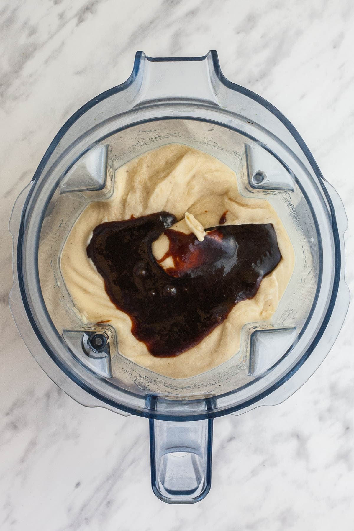 A blender from above with light ice cream and dark brown caramel sauce on top.