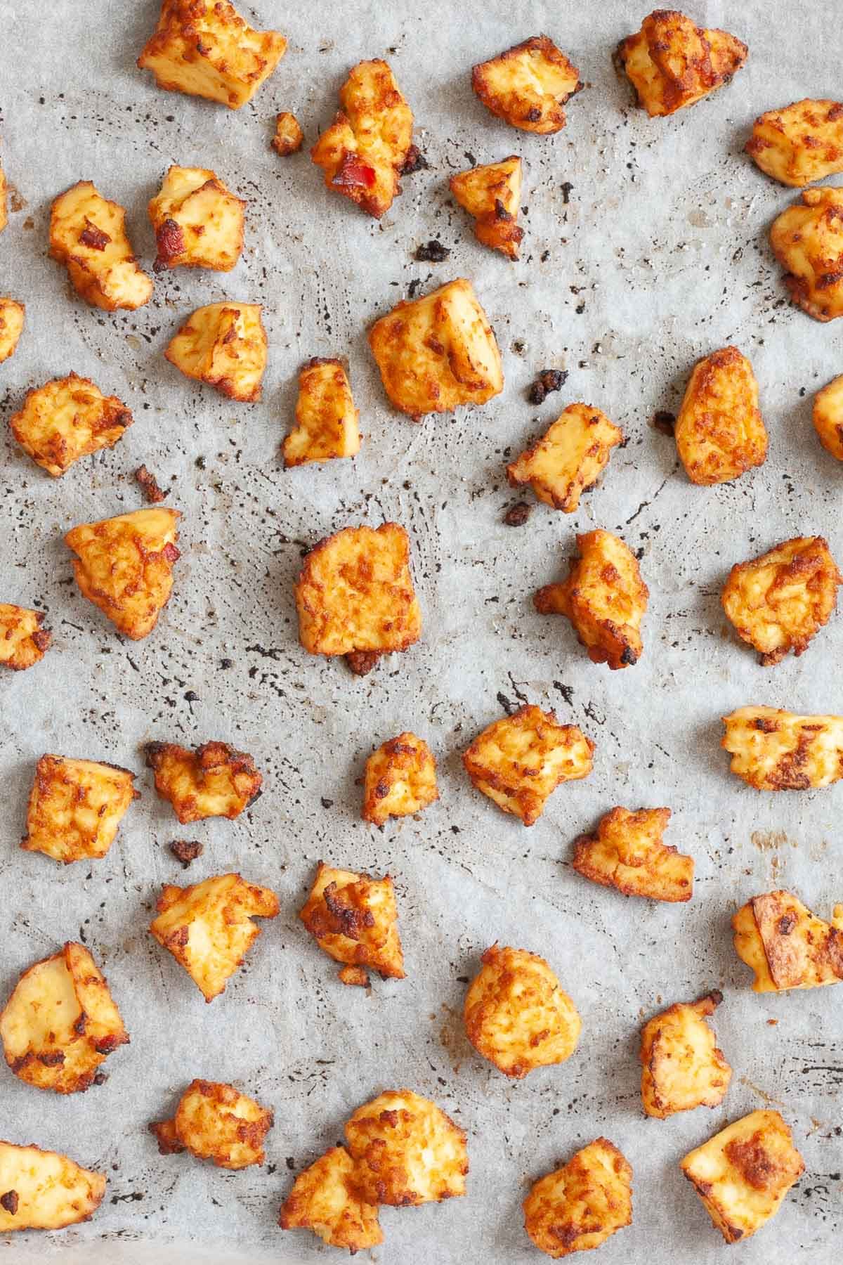 Torn tofu bites after baking having crispy brown crusts is placed in a parchment paper.