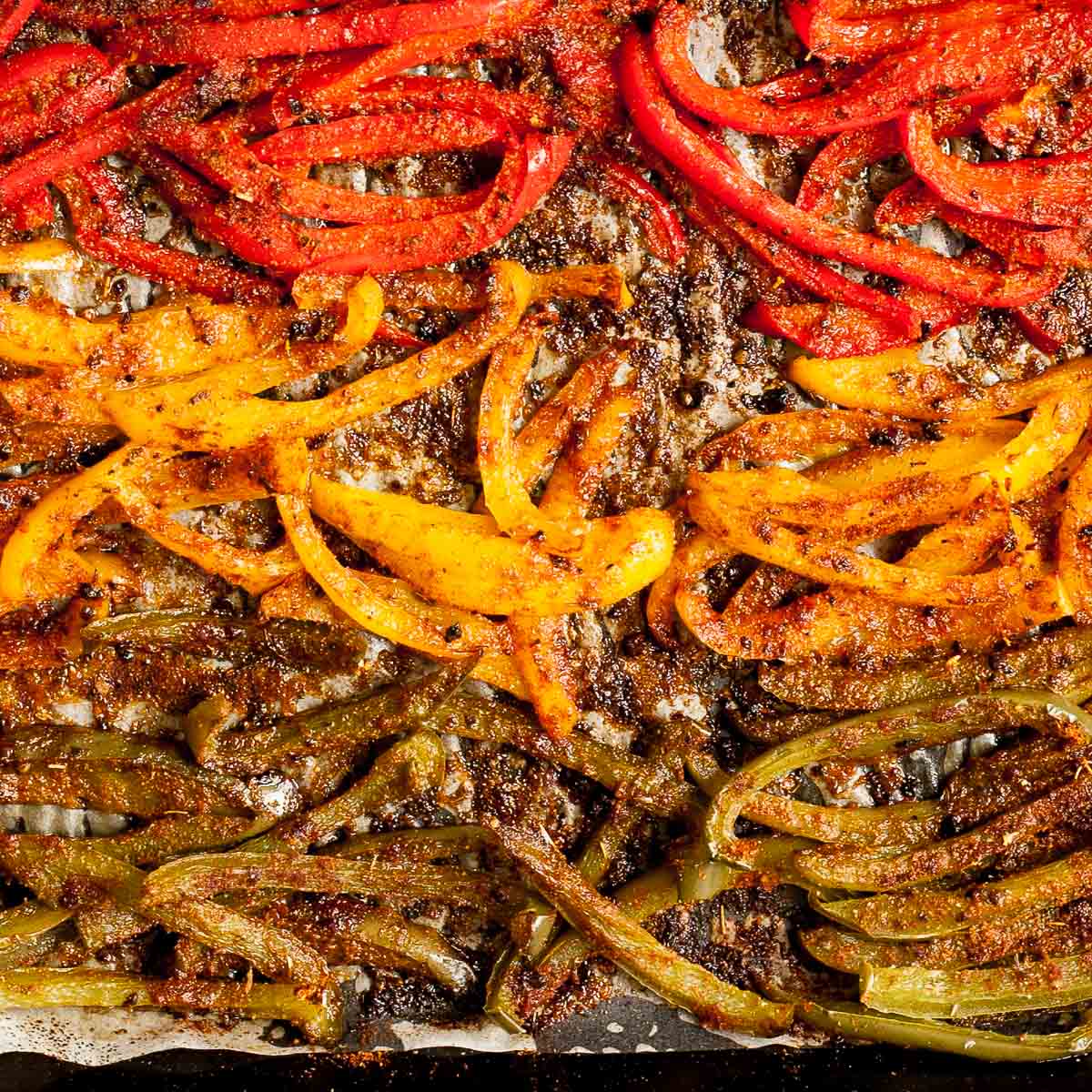 Close-up of roasted brown crispy seasoned red, yellow, green bell pepper strips and mushroom slices after baking.