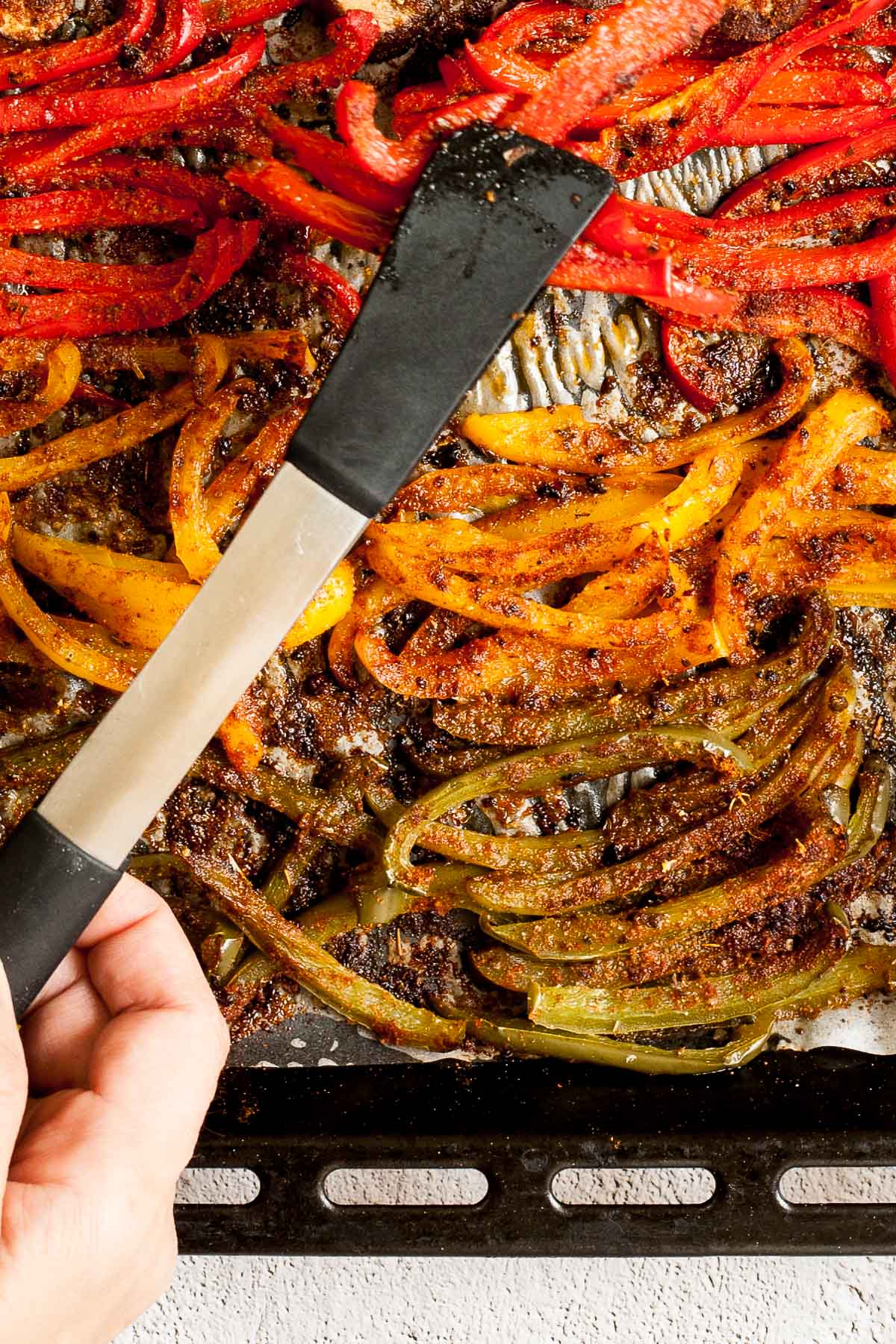 Close-up of roasted brown crispy seasoned red, yellow, green bell pepper strips after baking.