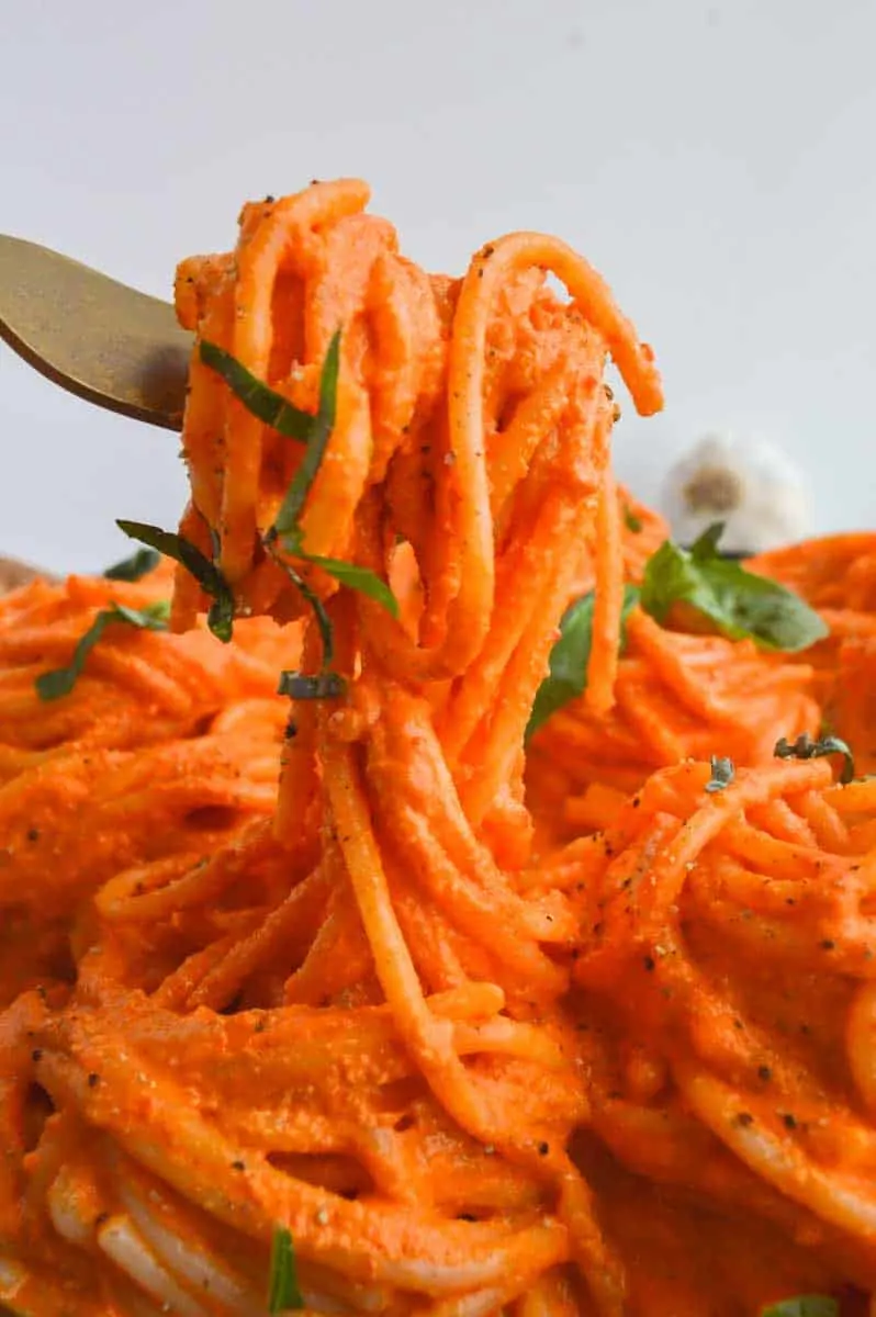 Vibrant orange sauce in spaghetti. A fork is lifting some of the pasta up.